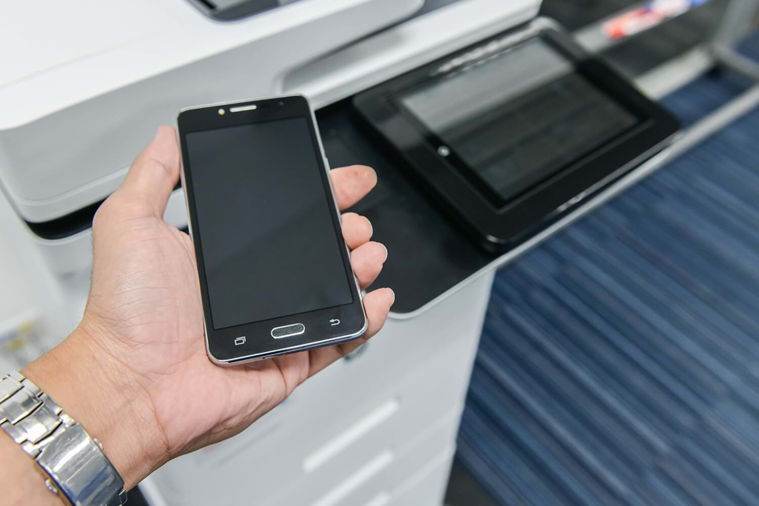 Close Up of Hand Holding Smart Phone in Front of Office Printer